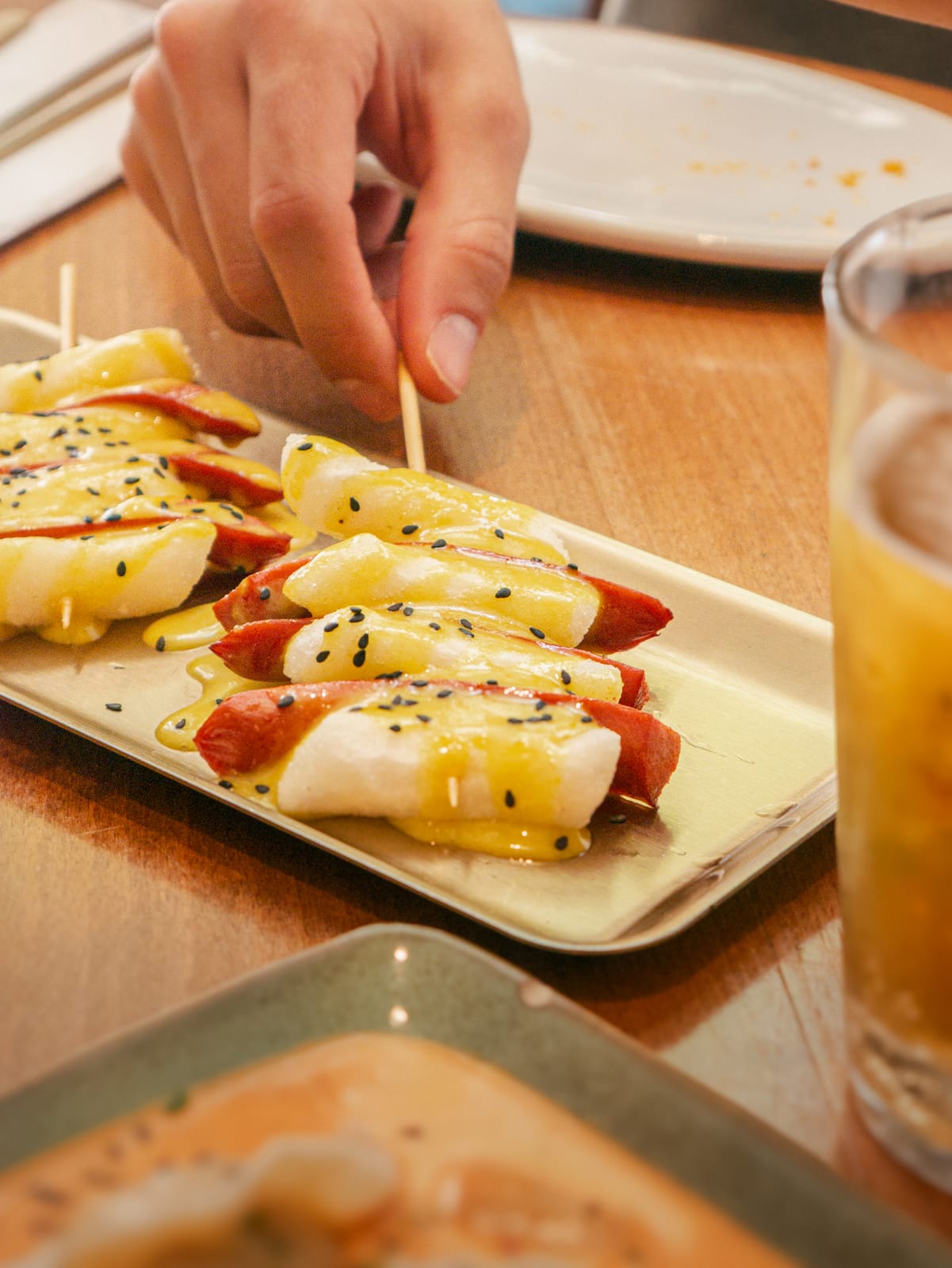 Brochetas de tteok envueltas en beicon con salsa de mostaza y sésamo