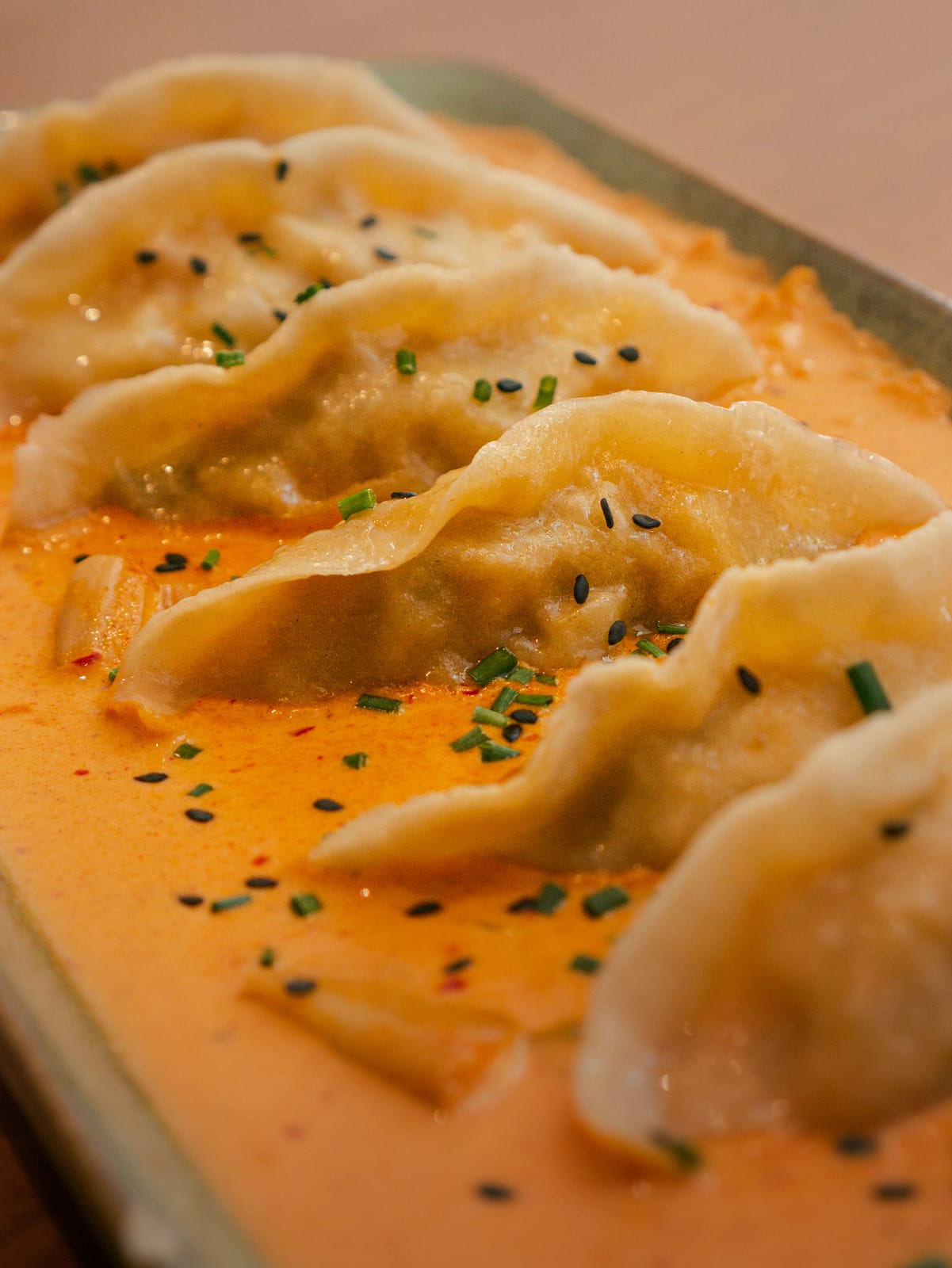 Empanadillas coreanas en salsa picante con cebollino y sésamo negro